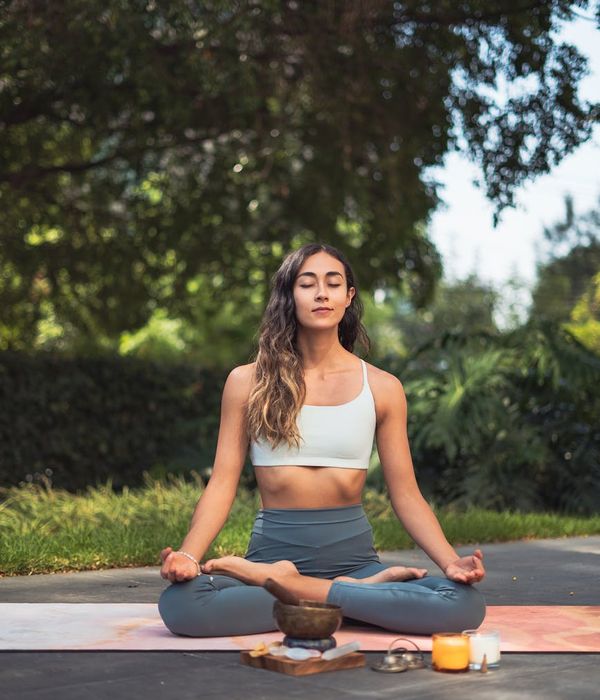 Person meditating peacefully on a yoga mat outdoors.