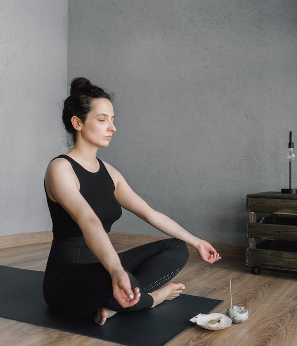 Smiling person unrolling a yoga mat in a sunlit room.